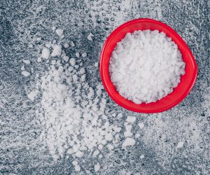 Sea salt in a red bowl and around on a gray textured background. top view.